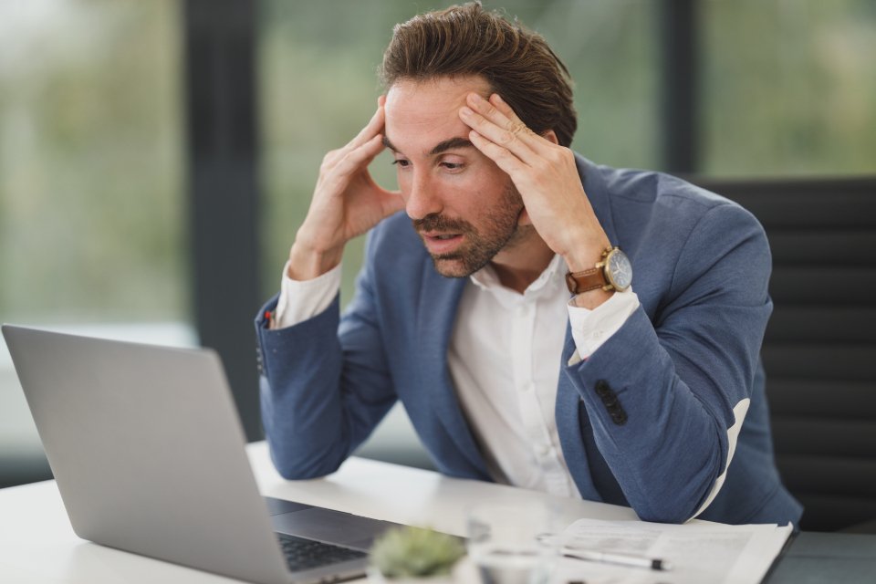 A merchant frustrated at a laptop showing a Shopify CSV import error screen